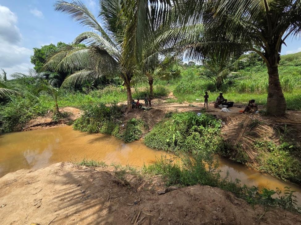 Community members collecting water from a muddy river in Fotobi, Ghana